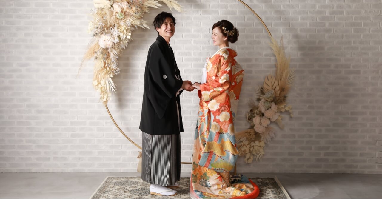 舞い落ちる花びらに掌をだす和装の新郎新婦