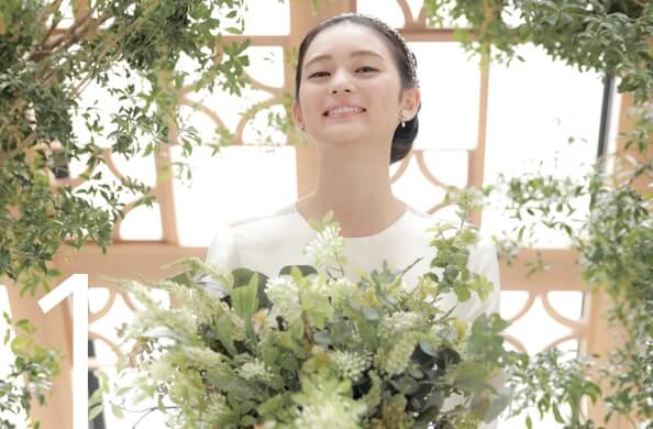 花束を手にチャペル神楽の大きなガラスの前に立つ花嫁